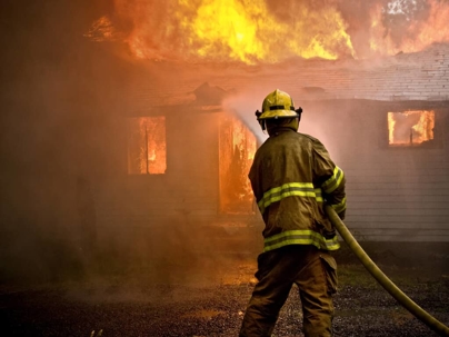 a firefighter spraying water on a burning building